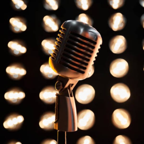 Vintage microphone on a stand, with a blurred background of warm, glowing lights.