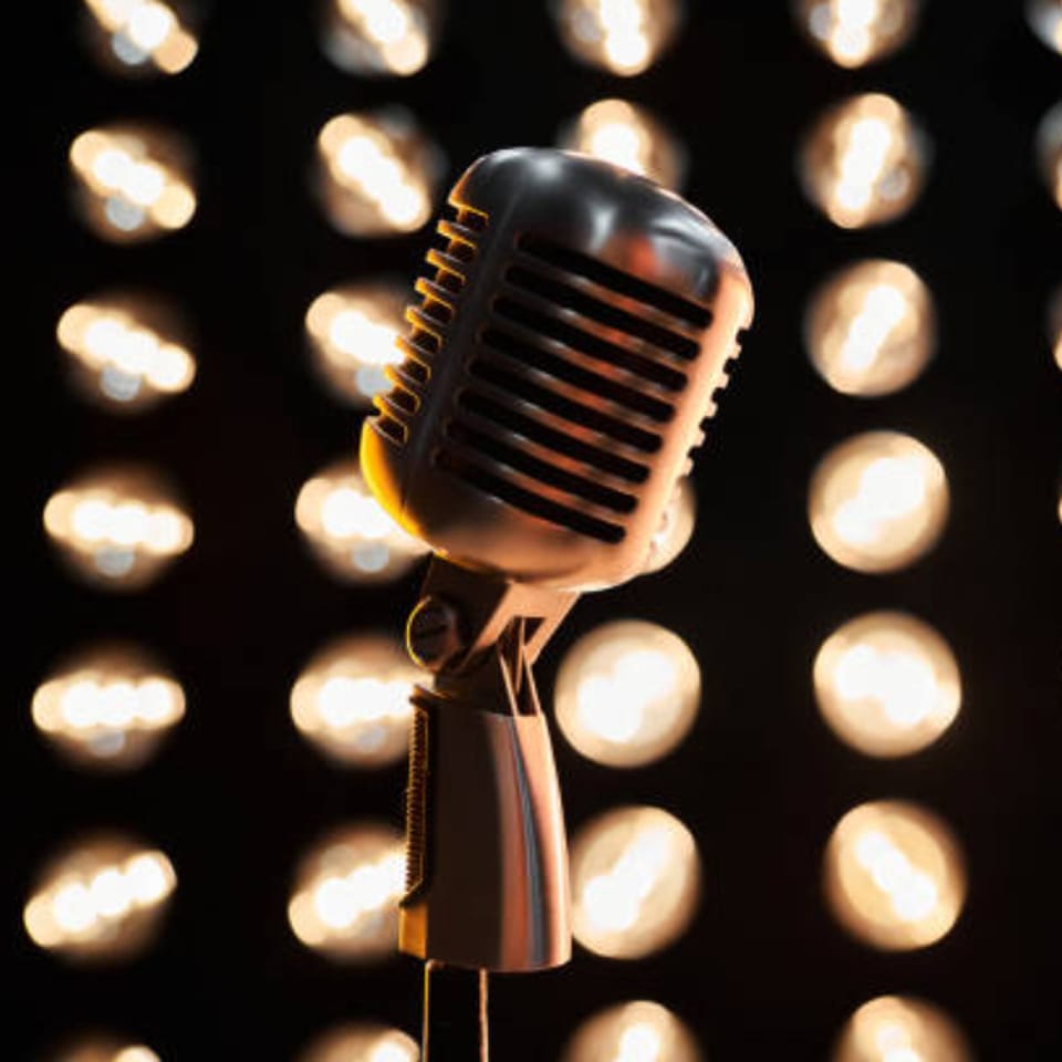 Vintage microphone on a stand, with a blurred background of warm, glowing lights.